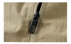 Close-up of khaki ripstop nylon jacket fabric with black metal zipper and cord puller