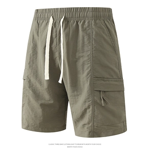 Detail of army green nylon cargo shorts featuring elastic drawstring waist and side flap pockets