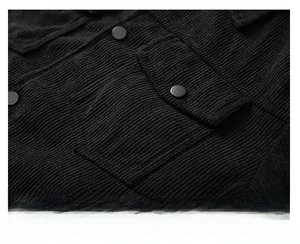 Detailed macro view of black corduroy jacket chest pocket with metal button and ribbed texture