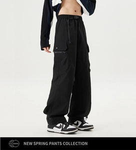 Detail of black cargo pants featuring elastic waist with buckle and side flap pockets