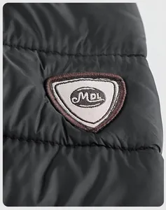 Detailed macro view of the triangular embroidered brand patch on black quilted jacket