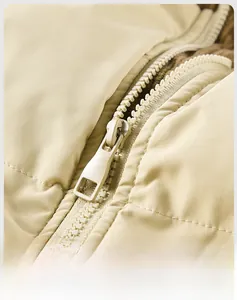 Close-up of the beige quilted jacket showing the durable plastic zipper and stitching