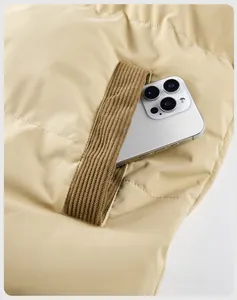Macro shot of side pocket with brown ribbed trim on beige padded jacket, fits smartphone
