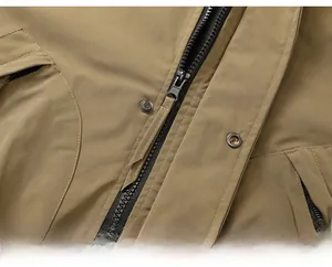 Detailed macro view of heavy-duty black zipper and metal snap button on khaki outdoor jacket
