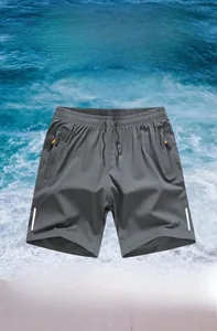 Detail of grey sport shorts with elastic waistband and orange zipper pocket accents