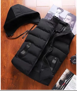 Vue détaillée du gilet noir à capuche avec surpiqûres horizontales sur du bois