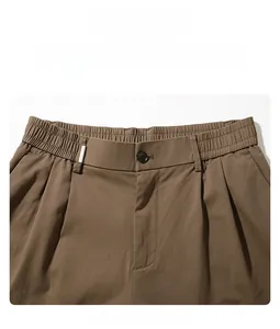 Detailed view of the elastic waistband and button closure on brown casual trousers
