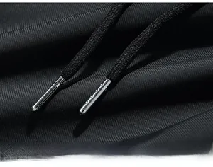 Détail du cordon de serrage réglable avec embouts métalliques sur le pantalon en soie glacée