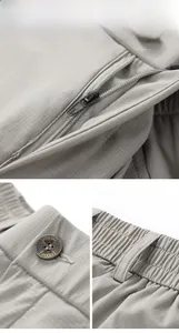 Detail of high-quality metal zipper and branded button on light grey men's trousers