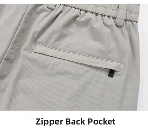 Detail of grid ripstop fabric and secure rear zipper pocket on light grey suit trousers