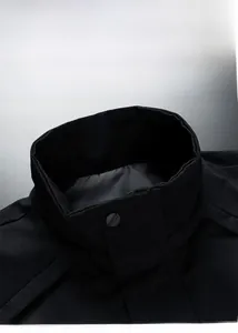 Detailed macro shot of a black stand-up collar jacket featuring a round metal snap button