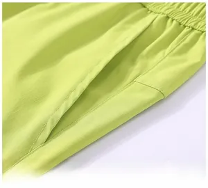 Detail view of fluorescent green ripstop cargo shorts with large side pockets and elastic waist
