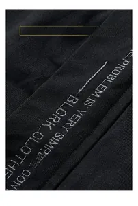 Detailed close-up of white letter embroidery on a casual black cotton jacket fabric