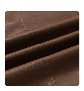 Detailed macro view of dark brown faux leather fabric with litchi grain and fine stitching