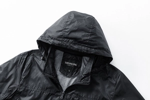 Detail of black hooded windbreaker collar with grey lining and metal zipper closure