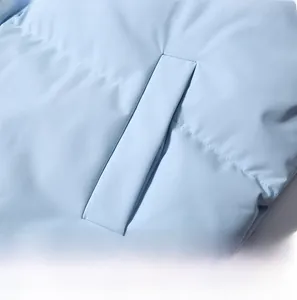 Detailed macro view of side pockets on a light blue puffer jacket with neat stitching