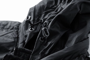Detail of ripstop fabric and adjustable hood drawstring on black outdoor jacket
