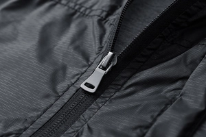 Detailed macro view of black ripstop fabric texture and matte gunmetal zipper on the jacket