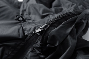 Macro detail of high-quality ripstop fabric with metal zipper and drawstring on black jacket