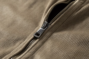 Macro shot of a high-quality metal zipper on tan waffle knit texture men's jacket fabric