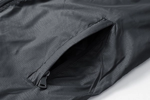 Detailed close-up of a black ripstop nylon hooded jacket featuring a metal zipper side pocket