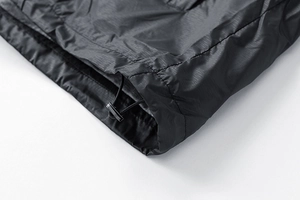 Detail of black ripstop fabric hem with adjustable elastic drawstring and plastic toggle