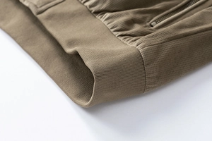 Detailed close-up of ribbed hem and metallic zipper on a suede texture jacket