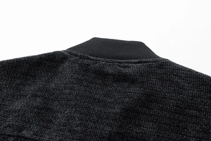 Macro shot of dark black waffle texture fabric and ribbed collar on a casual jacket