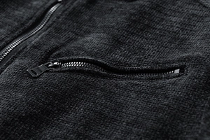 Macro detail of high-density textured dark grey jacket with premium metal zipper pockets