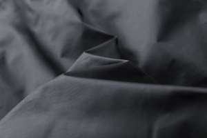 Macro shot of dark grey ripstop tech fabric with fine square weave and matte texture