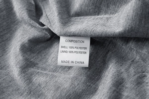 Detail of grey jacket wash label showing 100% polyester fabric material and care info