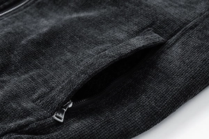 Macro shot of silver metal zipper and textured corduroy fabric on a dark gray jacket