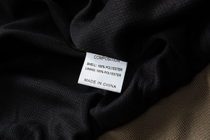 Macro detail of the fabric care label showing 100% polyester on black mesh lining