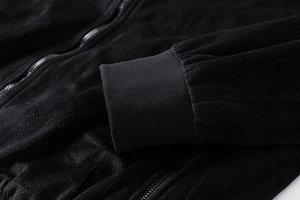 Detail of black corduroy jacket showing ribbed cuffs and high-quality metal zipper