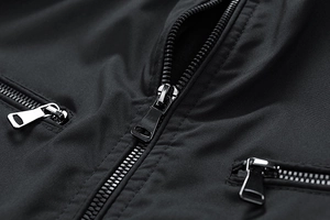 Detailed close-up of premium metal zipper pullers on a black windproof jacket