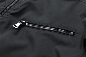 Detailed close-up of a silver metal zipper and smooth fabric on a men's black jacket