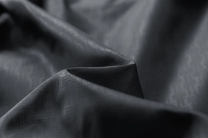 Macro close-up of dark grey high-density fabric with premium geometric jacquard texture