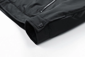 Detailed macro view of black jacket sleeve with metal snap button and zipper closure