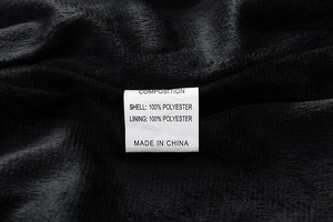 Close-up of fabric care label on men's jacket showing 100% polyester composition