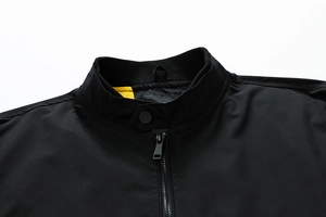 Close-up of black bomber jacket collar with snap button strap and yellow mesh lining