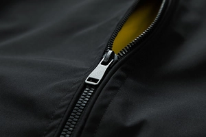 Detail of black flight jacket featuring contrast yellow lining and matte zipper