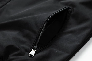 Detailed close-up of a high-quality zipper pocket on a black windproof bomber jacket
