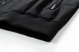 Detail of black flight jacket featuring ribbed hem and side zipper pocket construction