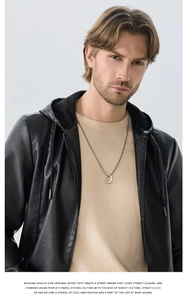 Close-up of black hooded PU leather jacket paired with beige knit sweater and silver necklace