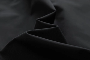 Detailed macro view of black minimalist flight jacket fabric showing smooth texture
