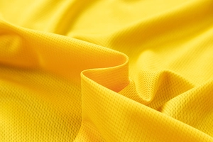 Macro shot of breathable yellow mesh fabric with honeycomb texture for bomber jackets