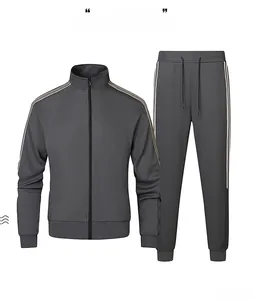 Flat lay of dark gray tracksuit with three side stripes on jacket and pants set