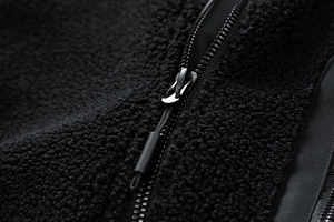 Close-up of black sherpa fleece texture and functional outdoor zipper detail