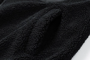 Detailed macro view of black lamb wool fabric texture and pocket stitching of jacket
