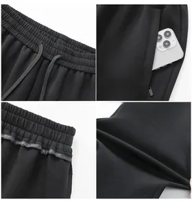 Detail of men's casual black joggers showing elastic drawstring waist and zipper pocket